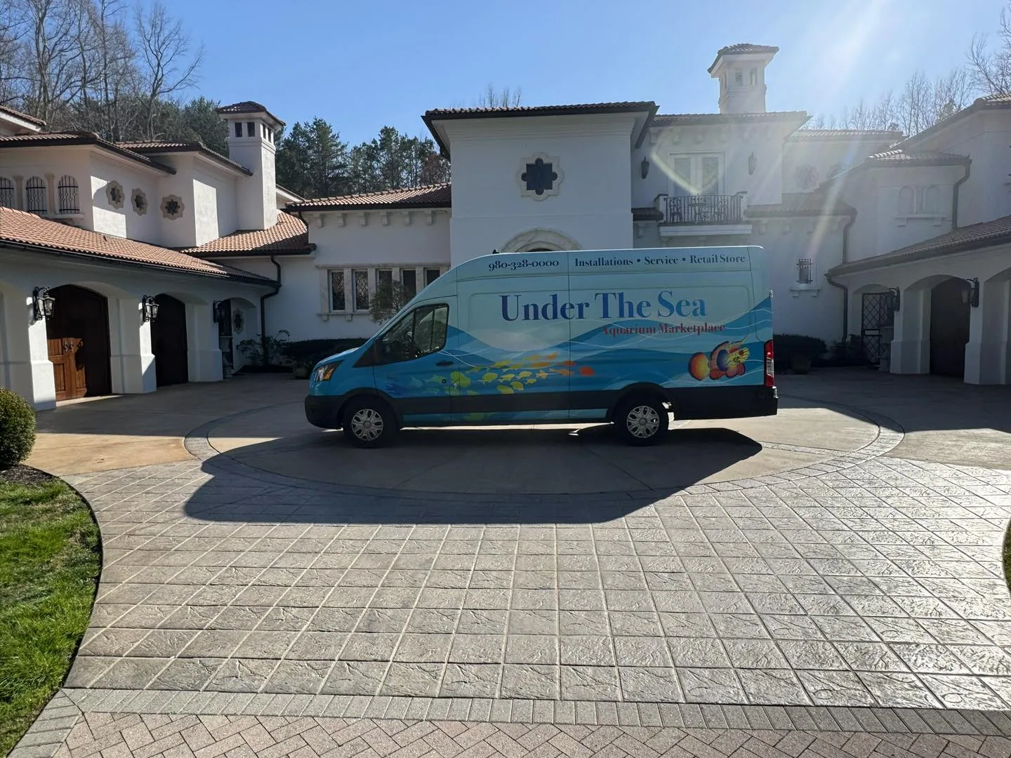 An Under The Sea service van parked in the driveway of a client's home for a scheduled aquarium visit
